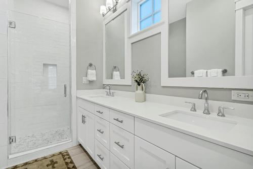 a white bathroom with two sinks and a shower at Sunshine Daydream in Port Aransas