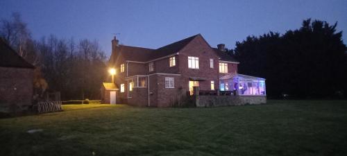 a large house at night with lights on it at Plumpton House in Ashford