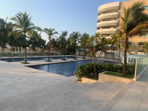 a swimming pool with palm trees and a building at Apartamento morros 922 in Cartagena de Indias