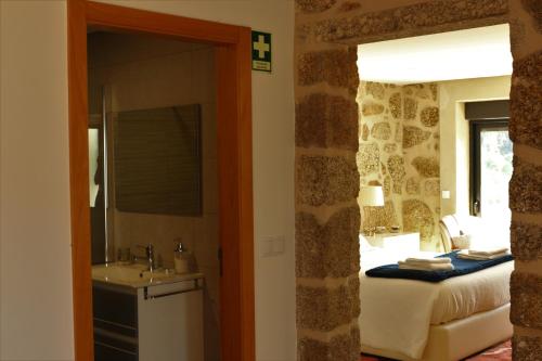 ein Badezimmer mit einem Schlafzimmer mit einem Bett und einem Waschbecken in der Unterkunft Vila de Campos - Gerês in Vieira do Minho