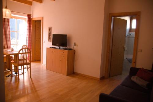 a living room with a television and a table with a chair at Messner Hof in Tires