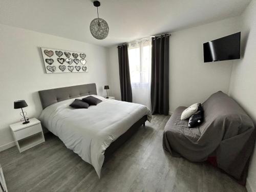 1 dormitorio con cama, sofá y TV en L'Entre Deux Rêves, en Beaumont-lès-Valence