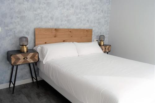1 dormitorio con cama blanca y mesa auxiliar en Apartamentos Son do Faro Fisterra, en Finisterre