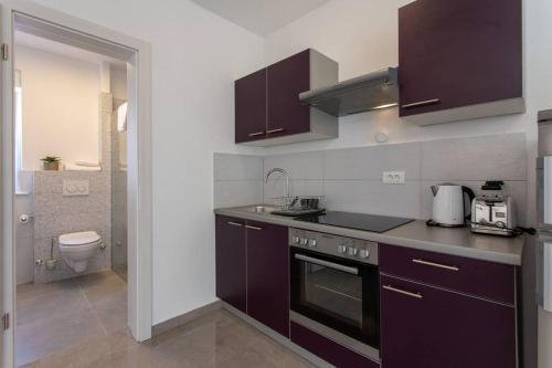 eine Küche mit lila Schränken und einem WC in der Unterkunft Teodora holiday house seafront in Kaštela