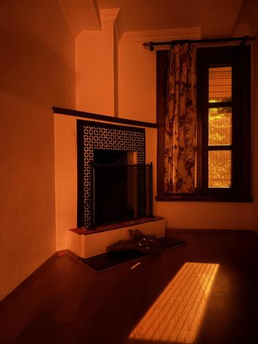 a living room with a fireplace and a window at village house kazdağları otel & restaurant in Edremit