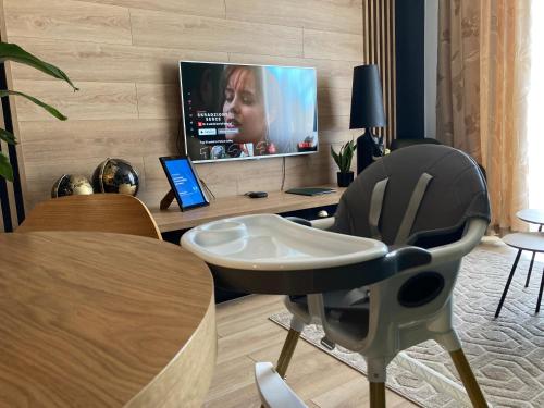 sala de estar con TV, mesa y silla en Apartamenty Termalne GREEN Apartment en Uniejow