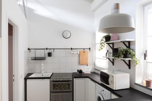 cocina con electrodomésticos blancos y encimera negra en Xenia Apartments - Moderno appartamento in Fondazione Prada, en Milán