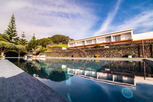 a swimming pool in front of a house at ANC Resort in Caloura