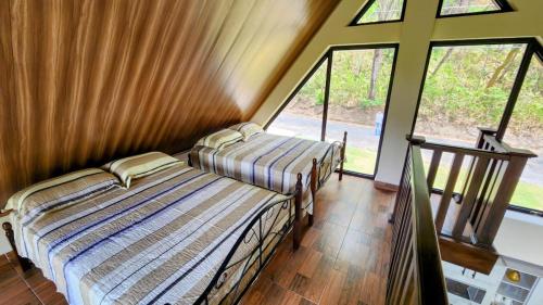 two beds in a room with large windows at Cabaña de montaña en Altos del María in Sorá