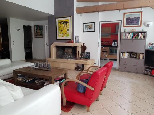 un salon avec une chaise rouge et une cheminée dans l'établissement Maison avec jardin à 15 mn de la Tour Eiffel, à Boulogne-Billancourt