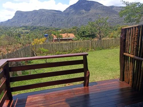 a wooden bench on a deck with mountains in the background at Pouso dos Sonhos Suítes Lapinha da Serra in Santana do Riacho