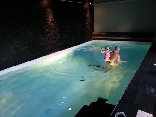 un homme et un enfant assis dans une piscine dans l'établissement Aqua Zen avec Piscine - Breizh location, au Guilvinec