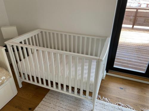 a white crib in a room with a window at Stunning 5BR 16 Bed Home with Finnish Sauna & Jacuzzi 340 m2 in Tampere
