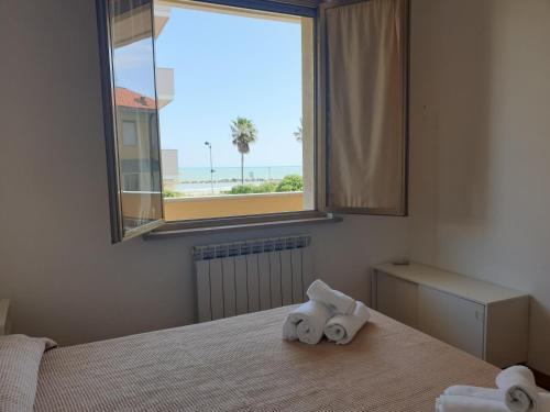 een slaapkamer met handdoeken op een bed met een raam bij My Beachouse in Montesilvano
