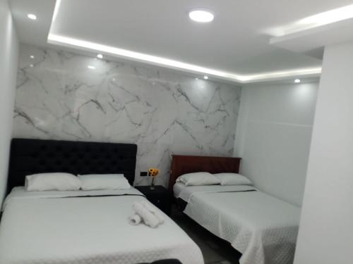 バーニョスにあるHostal Anaisの大理石の壁の客室内のベッド2台