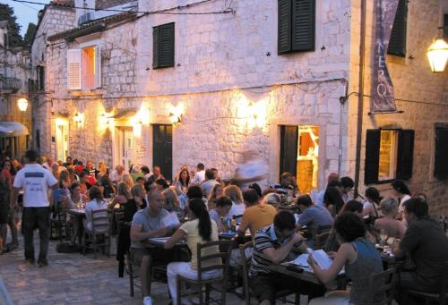 una folla di persone sedute ai tavoli fuori da un edificio di Cheap Sleep Marinero a Hvar