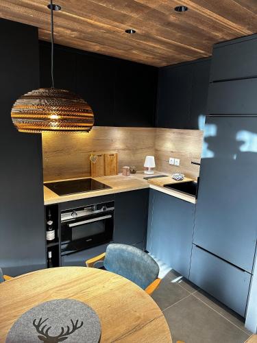 une cuisine avec des armoires noires et une table ainsi qu'une salle à manger dans l'établissement Chalet Cristal - Magnifique Appartement à 5mn du centre de La Clusaz, à Saint-Jean-de-Sixt