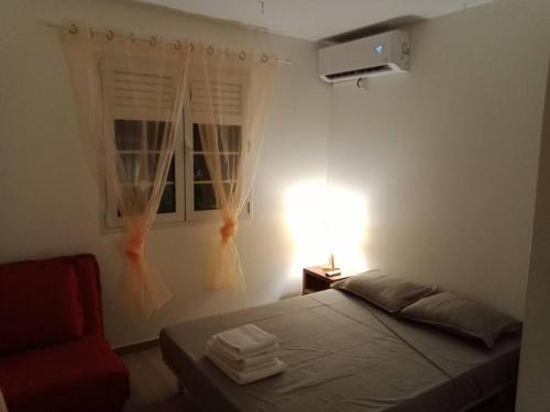ein Schlafzimmer mit einem Bett und einem roten Stuhl in der Unterkunft Martinique La petite maison dans la Colline in Le Lamentin