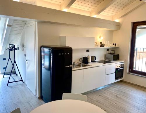 a kitchen with a black refrigerator and white cabinets at Casa di Nuvola -Residenza Lavinia - in Monforte dʼAlba