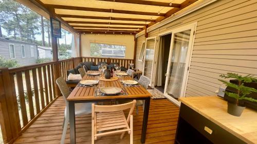 una terraza de madera con mesa y sillas. en Tiny house famille nature cap ferret, en Claouey