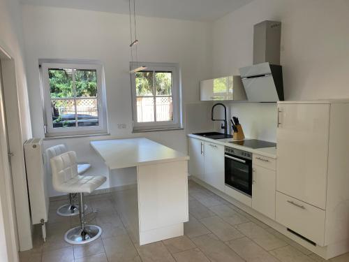 a kitchen with white cabinets and a table and a chair at Naabsuite in Neustadt an der Waldnaab