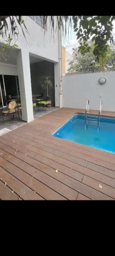 una piscina con terraza de madera junto a un edificio en Casa blanca, en Guadalajara