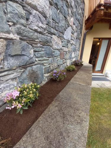 a stone wall with flowers in front of a house at PUNTA VITTORIA SUB 14 - RESIDENCE ANDERBATT GRESSONEY - 3 locali - CIR N 0010 in Staval