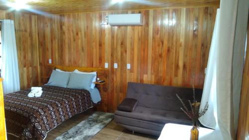 um quarto com uma cama e um sofá em POUSADA RECANTO DOS VAGA-LUMES em Urubici