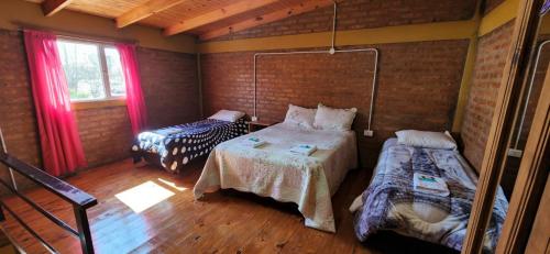 Antartida Apart Zapala في زابالا: غرفة نوم بسريرين في غرفة ذات أرضيات خشبية