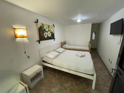a bedroom with a bed and a table and a lamp at Pousada Beijos y Abraços in Natal