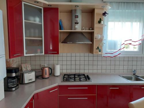 a kitchen with red cabinets and a stove top oven at Apartment Meli Varazdin in Varaždin