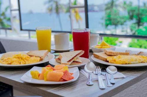 - une table avec des assiettes de produits pour le petit-déjeuner et des boissons dans l'établissement Hotel Sol Inn Santa Marta, à Santa Marta