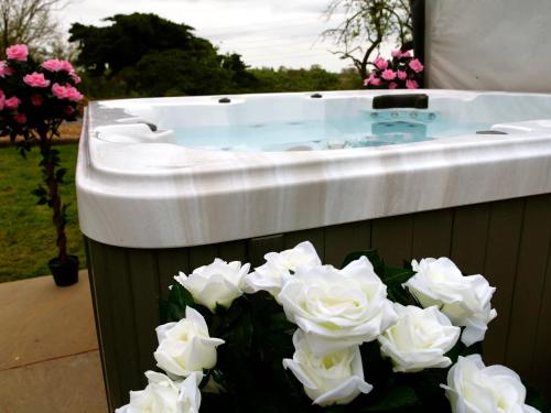 a jacuzzi tub with white flowers in front of it at Ultra Deluxe Versace Villa Hot Tub Cinema Room in Saffron Walden