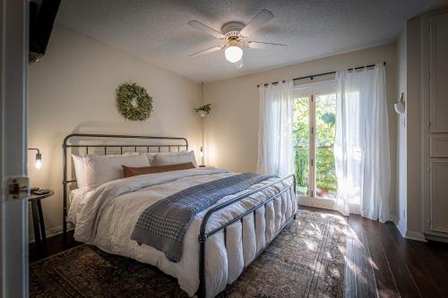 Lush, Enchanting Austin Oasis! في أوستن: غرفة نوم مع سرير مع مروحة سقف ونافذة