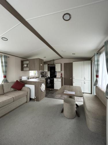 a living room with a couch and a kitchen at Delightful 2 bedroom Caravan, Pencnwc, New Quay in Cross Inn