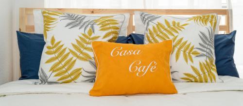 an orange pillow with the word casa cafe sits on a bed at B CasaCafé Madrid Pozuelo 2 Baño Fuera de la habitacion o COMPARTIDO in Pozuelo de Alarcón