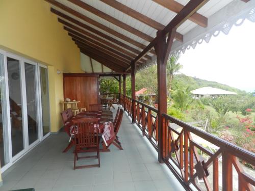 a porch with tables and chairs on a balcony at Résidence COCO D'ILES, Gite TI BAMBOU in Terre-de-Bas