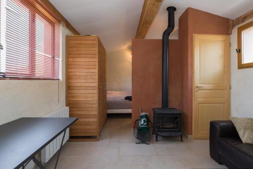 a living room with a stove and a bedroom at Maison du Manescau in Saint-Pierre-de-Vassols