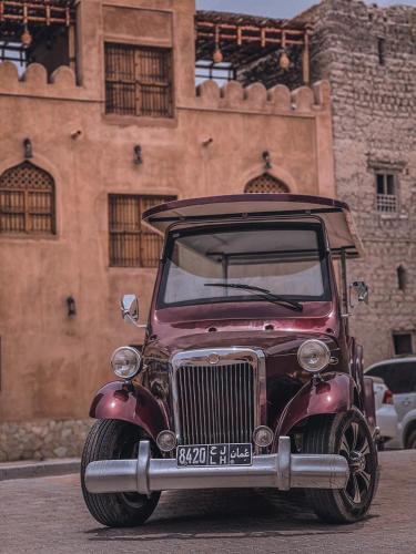 an old red car parked in front of a building at بيت الراحة Rest House in Nizwa