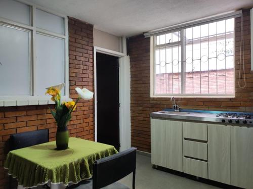 a kitchen with a table with a vase of flowers on it at Roma House N- suite Campin Movistar Ministerios Simón Bolivar in Bogotá
