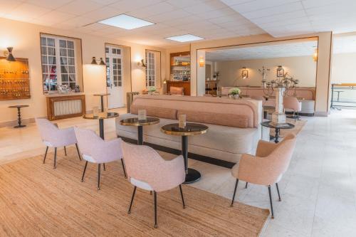 a bedroom with a bed and tables and chairs at Grand Hôtel de L'Espérance in Lisieux