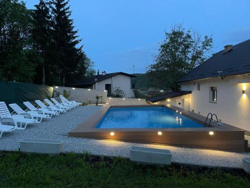 a swimming pool with white chairs and a house at Vila s bazenom deluxe - GTI in Zagreb