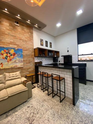 a living room with a bar with a couch and a kitchen at Apart Hotel Seg Total Lofts Encantadores in Mogi-Guaçu