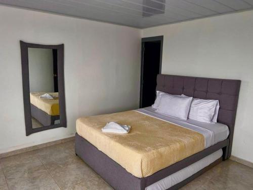 a bedroom with a large bed with a mirror at Hotel Campestre Atardecer Cafetero in Quimbaya