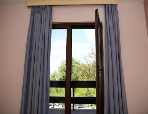 a glass door with blue curtains in a room at Hotel Restaurant Dreri in Tirana