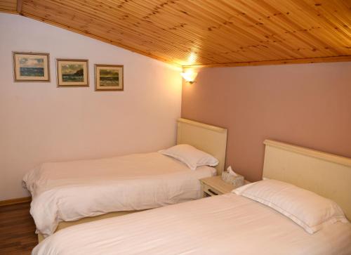 two beds in a room with wooden ceilings at Hotel Restaurant Dreri in Tirana