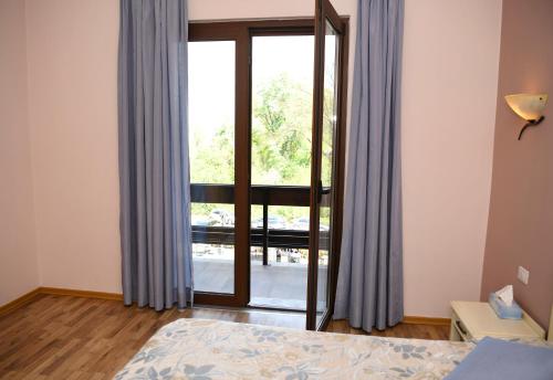 a bedroom with a large window with blue curtains at Hotel Restaurant Dreri in Tirana