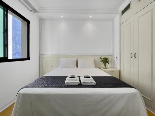 a white bedroom with a large bed with towels on it at Lindo Hotel na Paulista in São Paulo