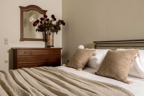 a bedroom with a bed with a mirror and a vase of flowers at Amalthia Villa in Mouzákion
