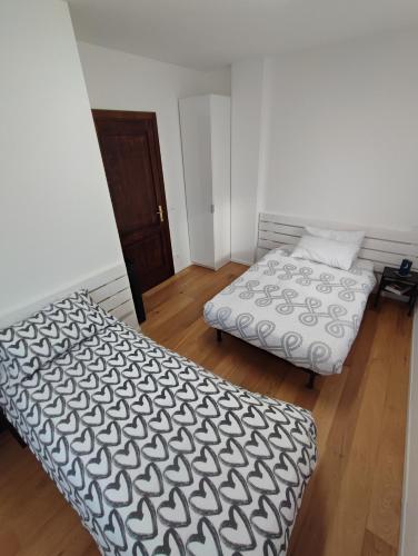 two beds in a room with wooden floors at La Casa di Priscilla in Fagagna